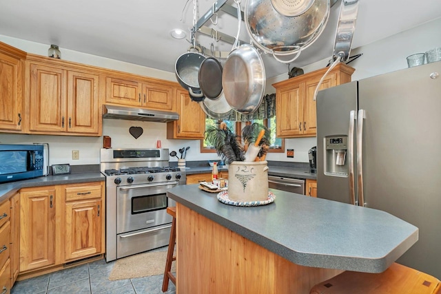 kitchen featuring a kitchen island, a kitchen bar, light tile patterned floors, and appliances with stainless steel finishes