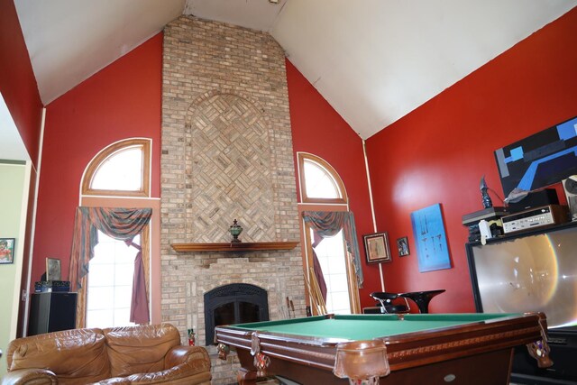 game room with pool table, high vaulted ceiling, and a brick fireplace