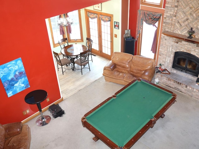 game room with a notable chandelier, a fireplace, pool table, and french doors