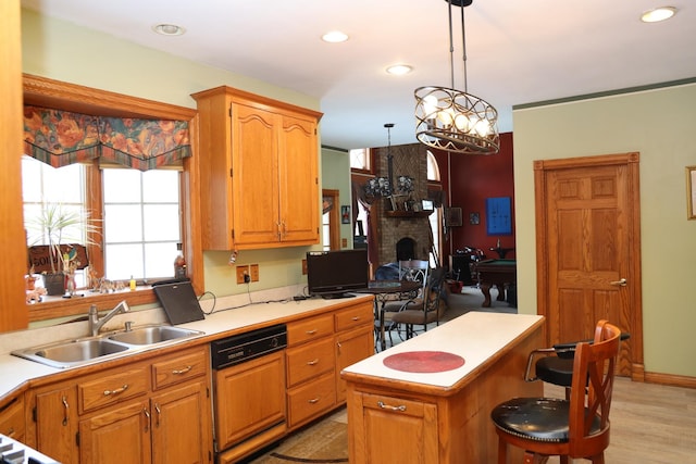 kitchen featuring sink, pendant lighting, dishwasher, a fireplace, and a kitchen island