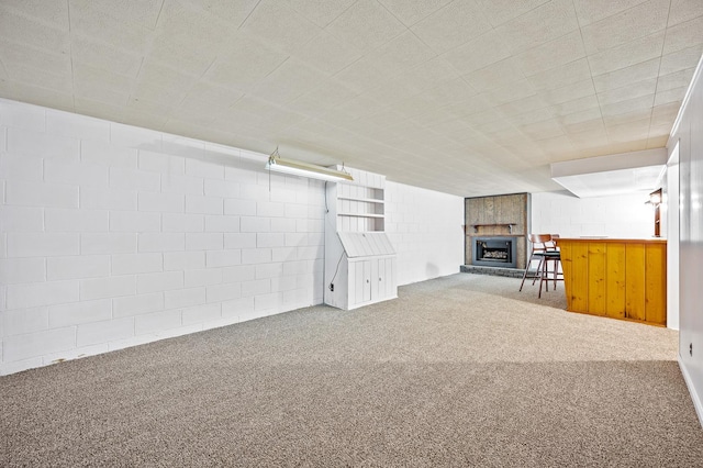 basement featuring carpet, a fireplace, and indoor bar