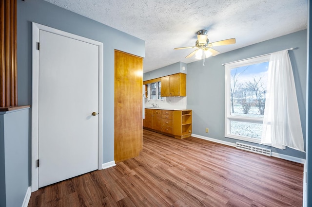 kitchen with a textured ceiling, light hardwood / wood-style flooring, ceiling fan, and sink