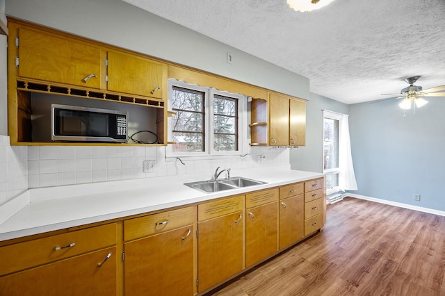 kitchen featuring a textured ceiling, decorative backsplash, light wood-type flooring, and sink