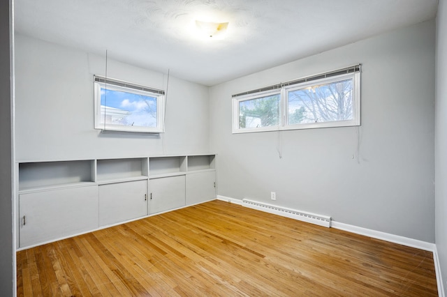 empty room with baseboard heating and hardwood / wood-style flooring