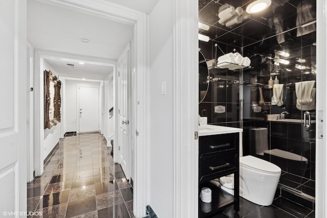 bathroom with vanity, toilet, a shower with door, and tile walls