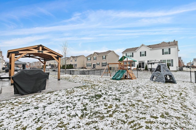 yard layered in snow featuring a gazebo and a playground