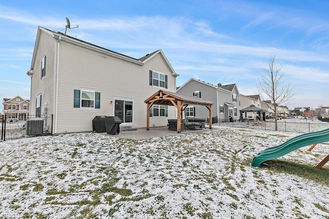 snow covered rear of property with a gazebo and a playground