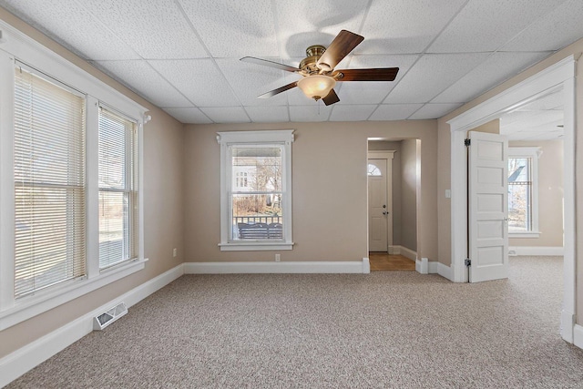 carpeted empty room featuring a drop ceiling and ceiling fan