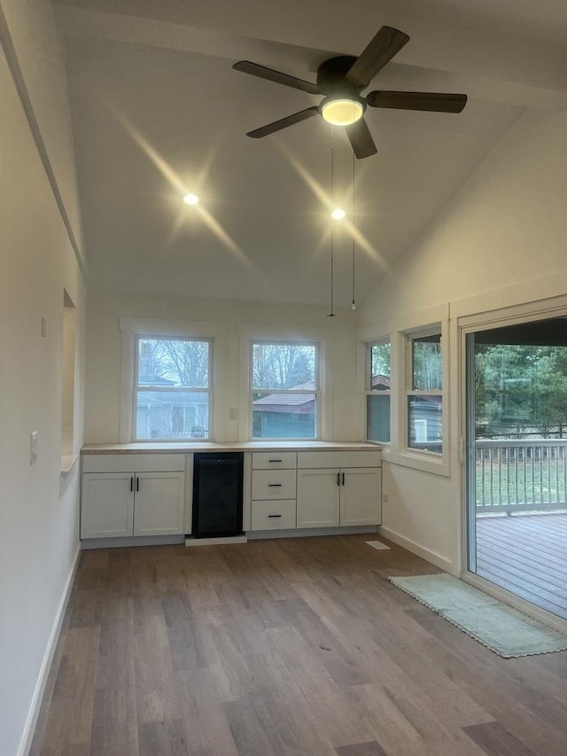 kitchen with ceiling fan, white cabinets, light hardwood / wood-style flooring, and lofted ceiling with beams