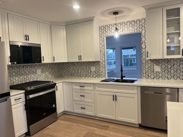 kitchen with light hardwood / wood-style flooring, sink, decorative light fixtures, white cabinetry, and stainless steel appliances