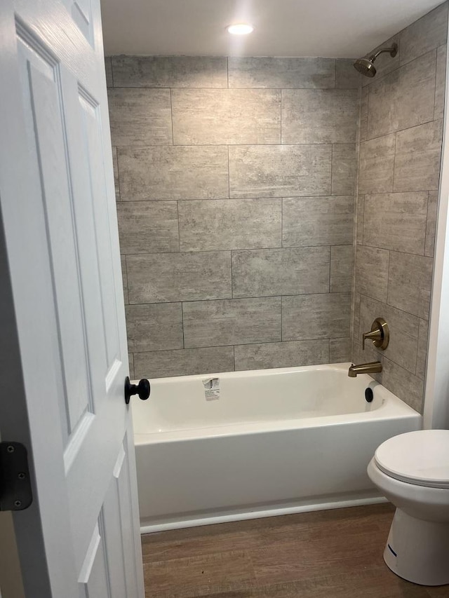 bathroom featuring hardwood / wood-style floors, toilet, and tiled shower / bath