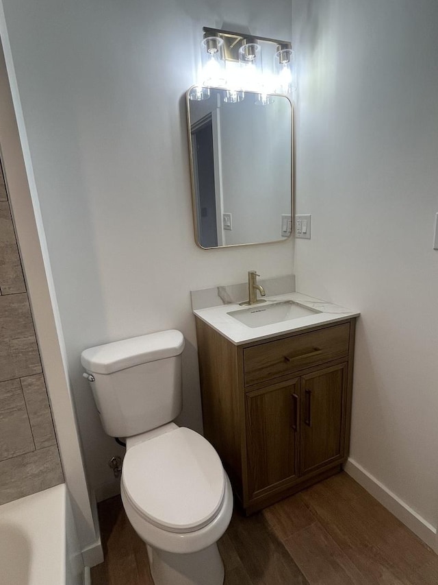 bathroom with hardwood / wood-style flooring, toilet, and vanity