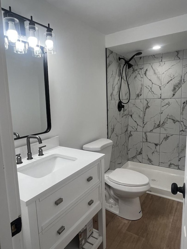 bathroom featuring vanity, toilet, hardwood / wood-style floors, and a tile shower