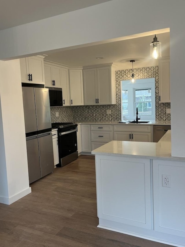 kitchen with white cabinets, sink, decorative light fixtures, dark hardwood / wood-style flooring, and stainless steel appliances