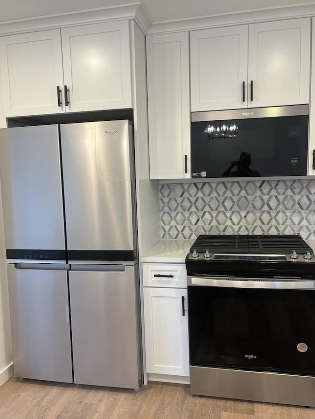 kitchen featuring white cabinets, light wood-type flooring, appliances with stainless steel finishes, and tasteful backsplash