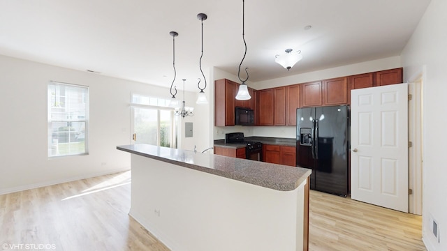 kitchen with hanging light fixtures, light hardwood / wood-style flooring, black appliances, and an inviting chandelier