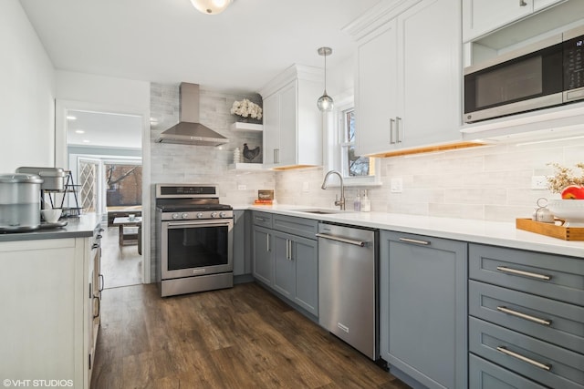 kitchen featuring hanging light fixtures, sink, gray cabinets, wall chimney range hood, and stainless steel appliances