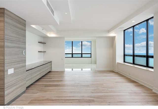 empty room featuring light wood-style floors, visible vents, and baseboards