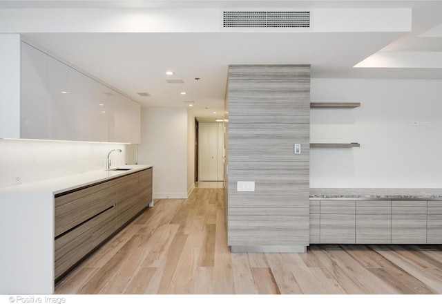 kitchen with light wood-style flooring, a sink, visible vents, open shelves, and modern cabinets