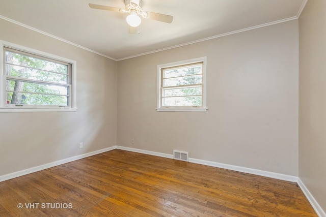 spare room with a healthy amount of sunlight, baseboards, visible vents, and crown molding