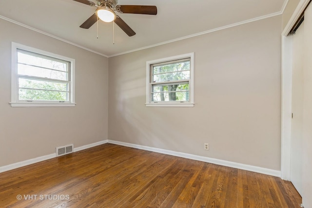 spare room with baseboards, visible vents, wood finished floors, and ornamental molding