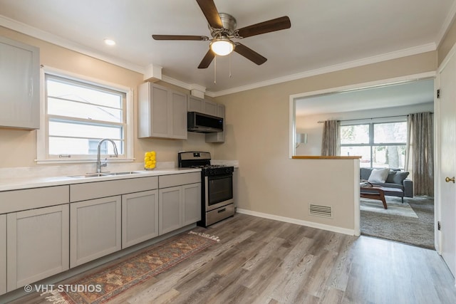 kitchen featuring visible vents, light countertops, crown molding, stainless steel range with gas cooktop, and a sink