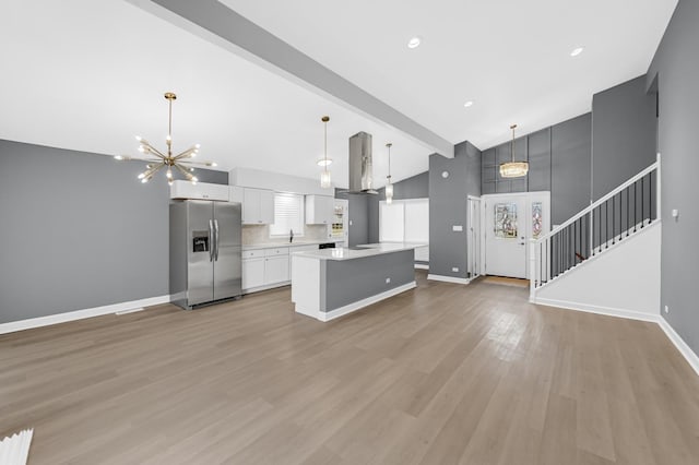 kitchen featuring stainless steel fridge, a kitchen island, light hardwood / wood-style floors, and hanging light fixtures