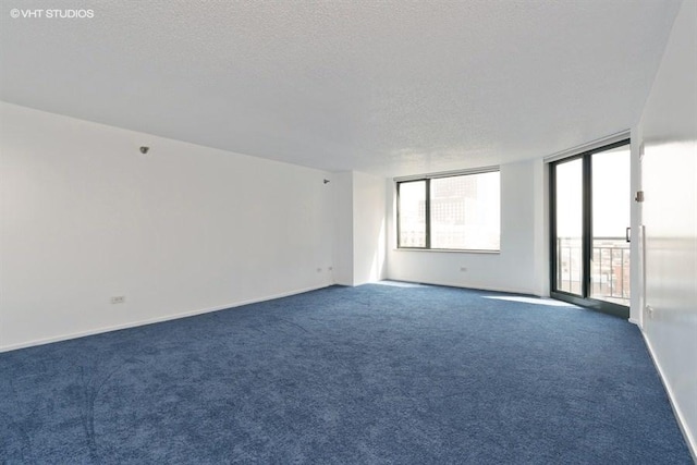 empty room with dark carpet and a textured ceiling