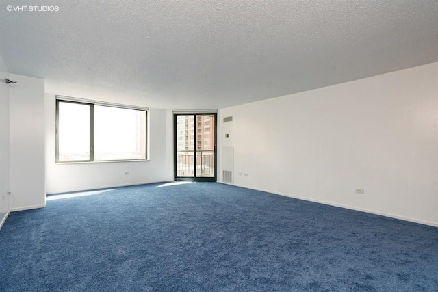 unfurnished room featuring a textured ceiling and dark carpet