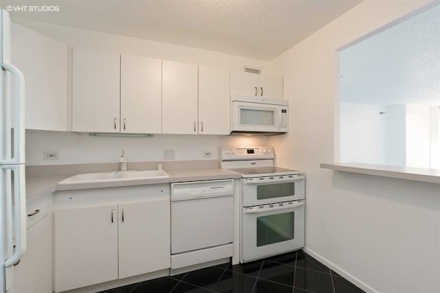 kitchen featuring white cabinets, white appliances, dark tile patterned floors, and sink