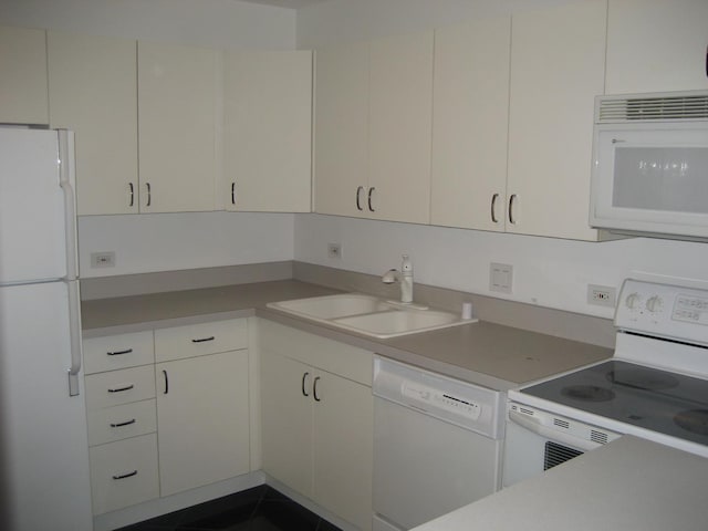 kitchen featuring white cabinetry, sink, dark tile patterned floors, and white appliances