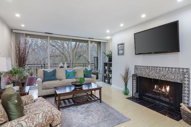 living room featuring hardwood / wood-style floors, expansive windows, and a tiled fireplace