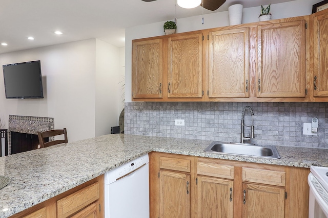 kitchen with white appliances, backsplash, light stone counters, and sink