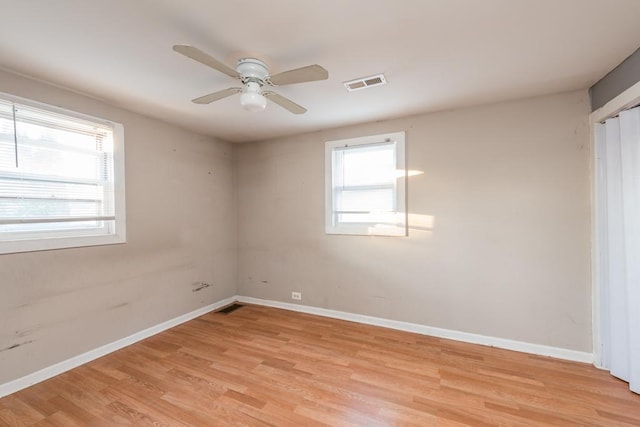 empty room with a wealth of natural light, ceiling fan, and light hardwood / wood-style floors