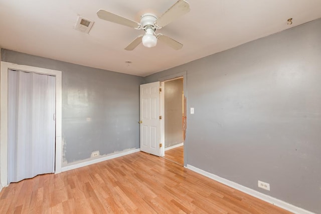 unfurnished bedroom with ceiling fan, light wood-type flooring, and a closet