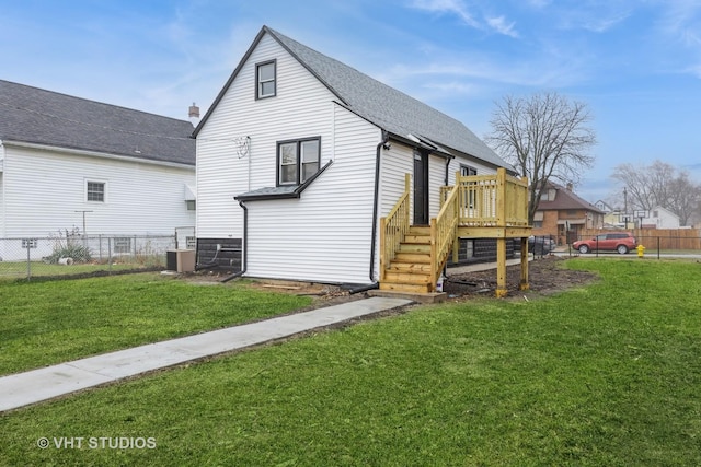 rear view of house featuring a deck, central air condition unit, and a lawn