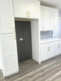 kitchen featuring backsplash, white cabinetry, and dark hardwood / wood-style flooring