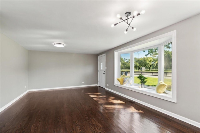 unfurnished room with dark hardwood / wood-style floors and an inviting chandelier