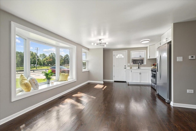 unfurnished living room featuring dark wood-type flooring and a notable chandelier