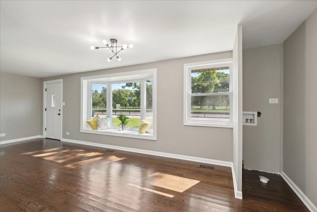 interior space with dark hardwood / wood-style floors, a healthy amount of sunlight, and a notable chandelier