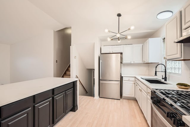 kitchen with sink, light hardwood / wood-style flooring, decorative light fixtures, white cabinetry, and stainless steel appliances