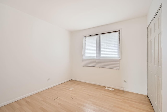 unfurnished bedroom with light hardwood / wood-style flooring and a closet