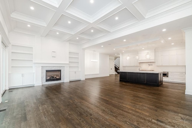 unfurnished living room with dark hardwood / wood-style flooring, beam ceiling, a high end fireplace, and built in features