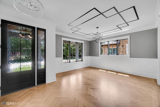 foyer with crown molding, light parquet flooring, and a notable chandelier