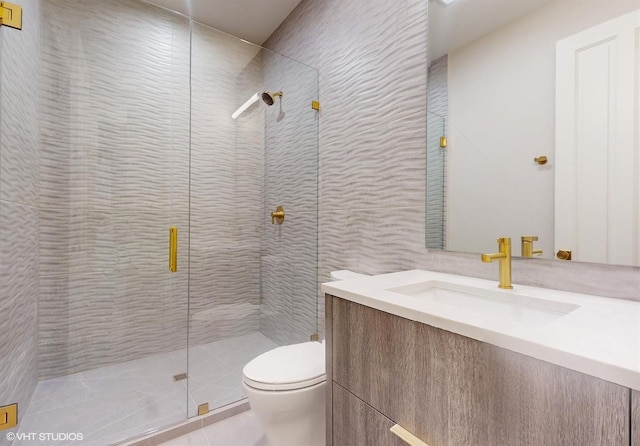 bathroom with a shower with door, vanity, tile patterned floors, and toilet