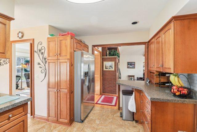 kitchen featuring stainless steel fridge with ice dispenser and dark stone counters