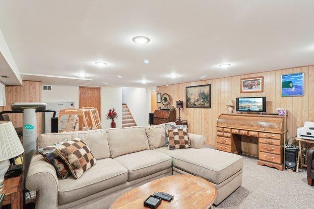 carpeted living room with wood walls