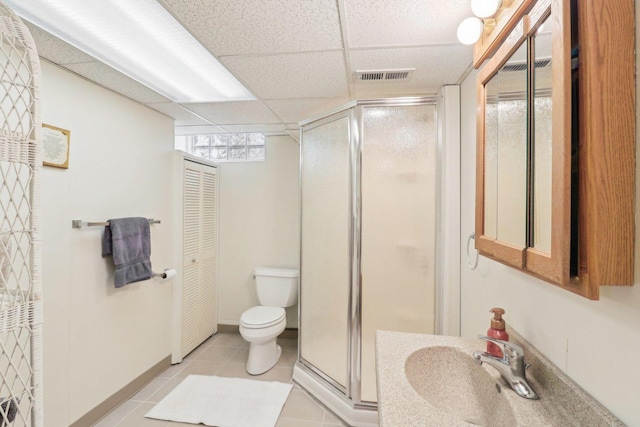 bathroom featuring tile patterned flooring, a drop ceiling, a shower with shower door, and sink