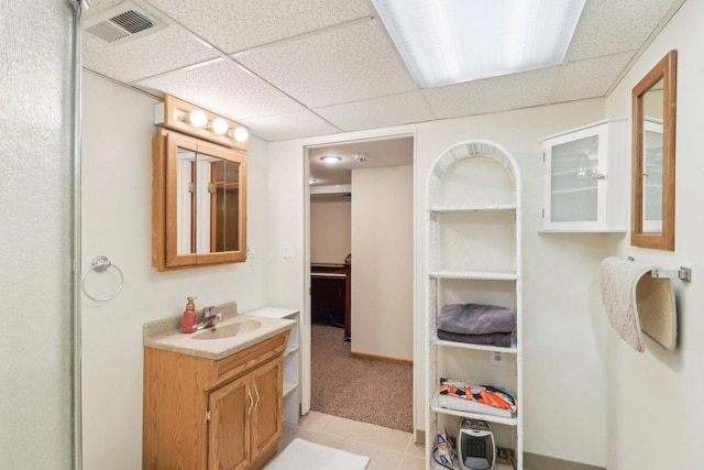 bathroom with a paneled ceiling, tile patterned flooring, and vanity