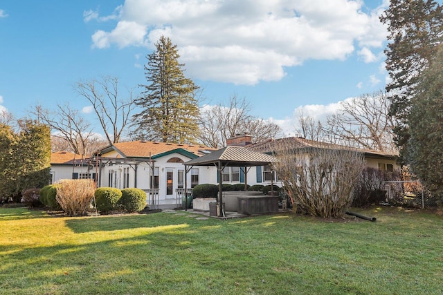 view of front of home with a front yard, a gazebo, and a hot tub